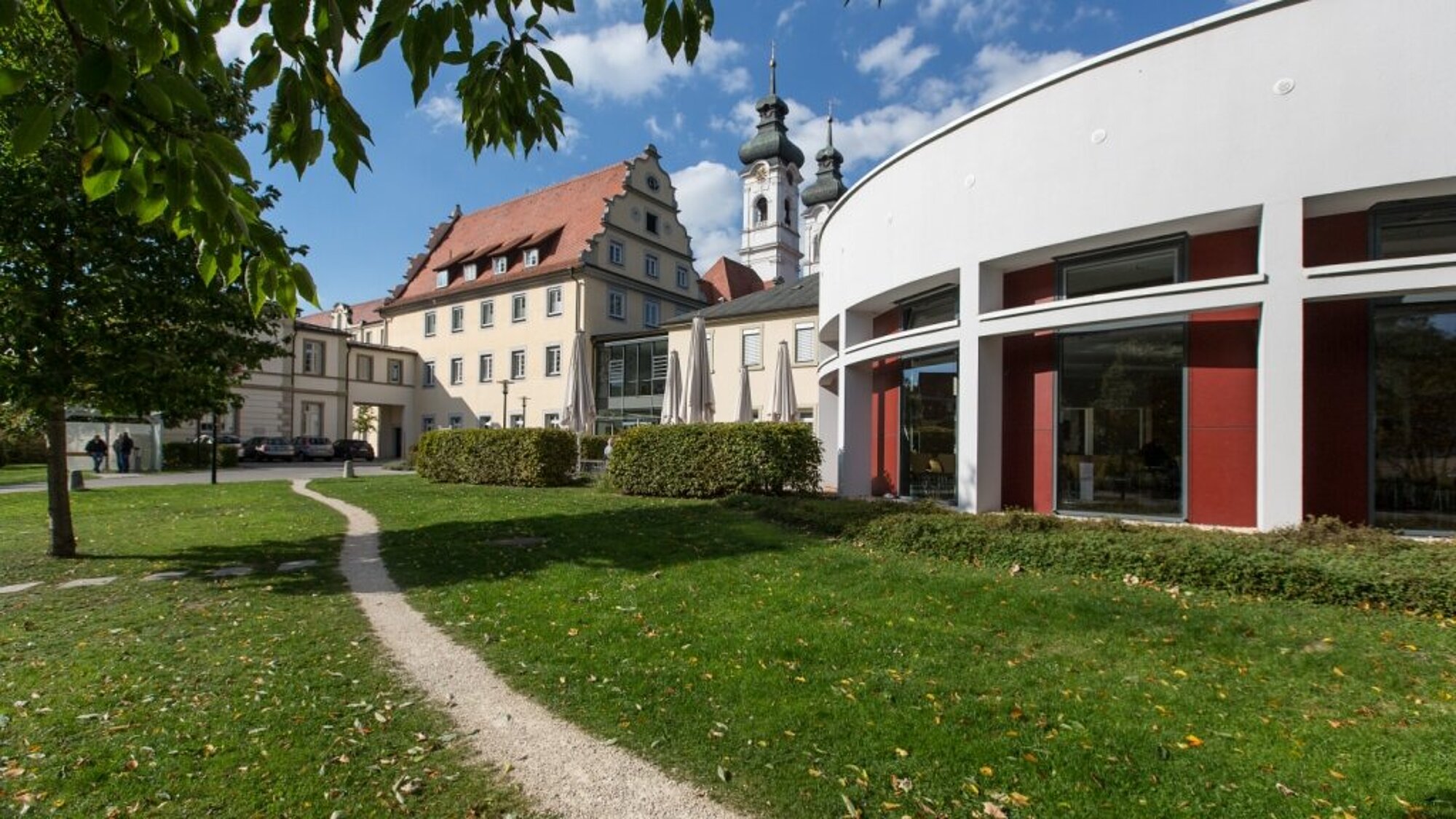 ZfP-Standort Zwiefalten Ein schmaler Fußweg verläuft an einem Rundbau vorbei.