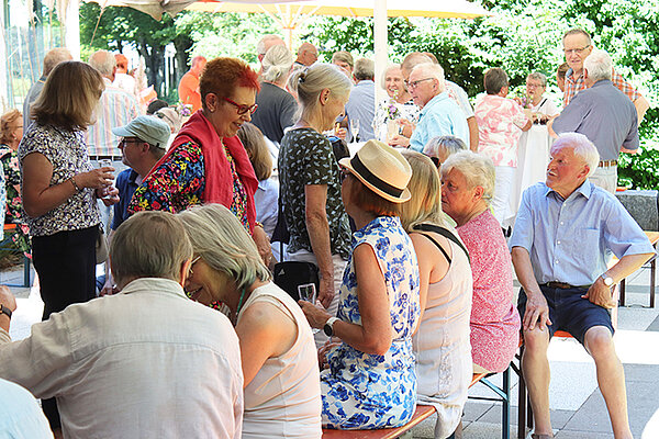 Ein große Gruppe Seniorinnen und Senioren sitzen im Freien zusammen.