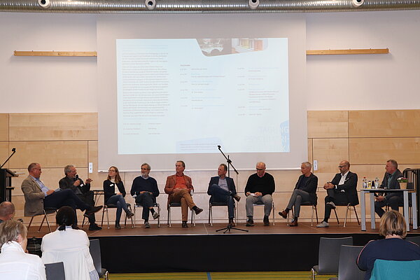 Eine Gruppe Menschen sitzt auf einer Bühne. 