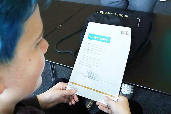 Ein Junge hält eine Urkunde in den Händen. Darauf steht "ich war dabei".