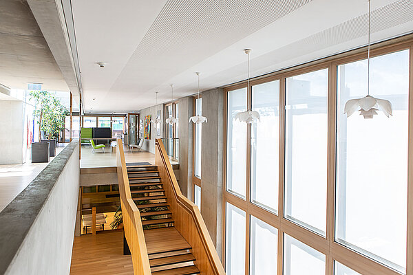 SINOVA Klinik Friedrichshafen Eine Treppe aus hellem Holz in einem lichtdurchfluteten Treppenhaus.