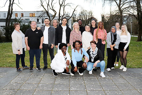 Rund 15 junge Menschen posieren ausgelassen für ein Gruppenbild.